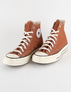 a pair of brown converse sneakers with white laces on the top and bottom,