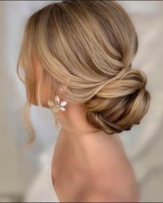 a woman with blonde hair in a low updo and flower earrings on her head