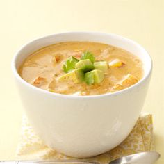 a white bowl filled with soup on top of a yellow napkin next to a spoon