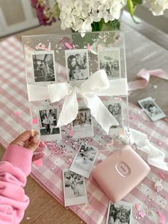 a pink and white photo frame with photos on the table next to it, surrounded by confetti