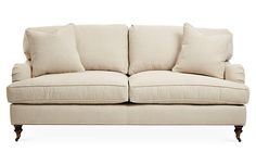 a white couch with four pillows on it's back and two sides facing each other