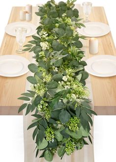 the table is set with white plates and greenery