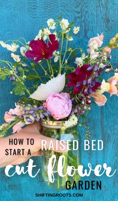 a person holding a mason jar filled with flowers and the words how to raise bed start a cat flower garden