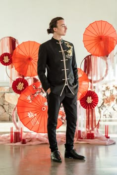 a man standing in front of red and orange umbrellas