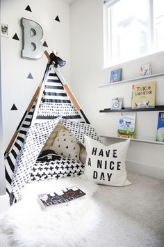 a teepee tent in the corner of a child's room with black and white decor