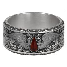 a silver ring with a red stone in the middle and an ornate design on it