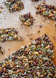 several pieces of pistachio on a cutting board with nuts scattered around them and one slice missing