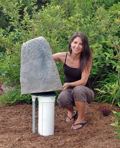 a woman kneeling down next to a large rock