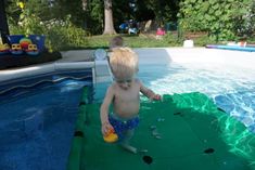 a little boy standing in the pool playing with a ball