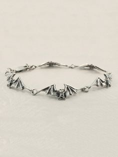 "This sculptural bat bracelet consists of 5 detailed bats linked wing tip to wing tip creating a beautiful scalloped pattern. 5 bat links is 6 1/4\" in length and 6 bat links is 7 1/4\" in length and fits most wrists. Take flight with these magical creatures! This item usually ships the same or next business day All Marty Magic Jewelry is packaged in a beautiful box, embossed with the gold foil Marty Magic dragon logo. Perfect for any occasion! Designed in Santa Cruz California by Marty Magic. M Cheap Spooky Silver Jewelry, Bat Bracelet, Magic Jewelry, Dragon Logo, Magic Dragon, Bat Jewelry, Linked Bracelet, Jewelry Halloween, Santa Cruz California