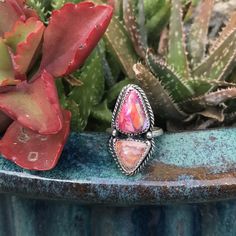 A pink, orange, and bronze composite teardrop stone is paired with a Mexican Fire Opal stone.  The opal has a pinkish orange purple flash that compliments the Spiny Oyster. The stones were set in sterling silver bezels with decorative twisted wire.  The setting is soldered to a fine silver hammered ring band size 4 1/2 but can be made larger up to size 6 1/2. The stones plus settings measure 1 1/8" by 5/8". Cowgirl Bling, Hippies, Spiny Oyster Ring, Pink Jewerly, Cowgirl Ring, Silver Hammered Ring, Silversmithing Jewelry, Purple Flash, Pinkish Orange