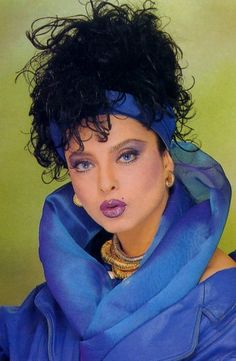 a close up of a person wearing a blue scarf and necklace with her hair blowing in the wind