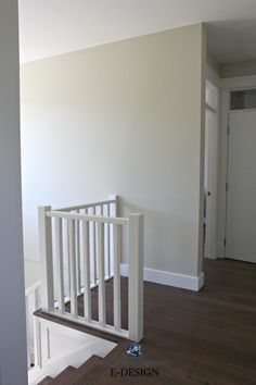 an empty room with white railings and wood flooring in front of the door