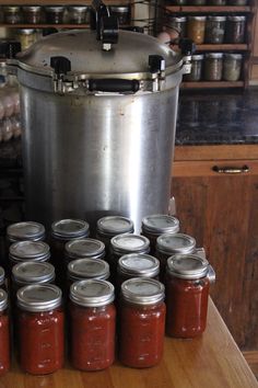 a large pot sitting on top of a wooden table filled with lots of canning jars