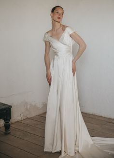 a woman in a white dress standing on a wooden floor with her hands on her hips