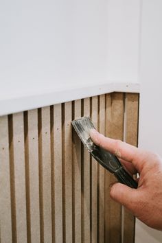 a person is using a brush to clean the radiator on a wall with wood slats