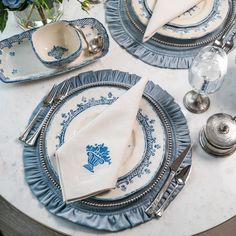 the table is set with blue and white plates, silverware, and napkins