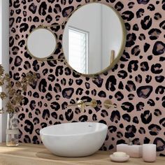 a bathroom with a leopard print wallpaper and a round mirror on the wall next to a sink