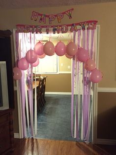 a birthday party with balloons and streamers hanging from the ceiling, in front of a doorway