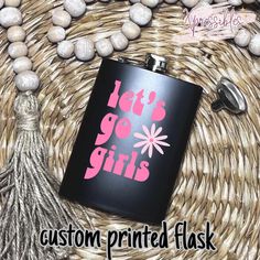 a flask with the words let's go girls on it next to some rocks