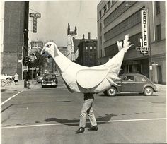 a man walking across a street holding an inflatable animal