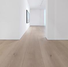 an empty room with white walls and wood flooring is seen in this image from the side