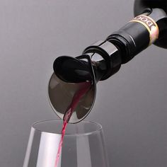 a wine glass filled with red wine being poured into it by someone pouring the wine