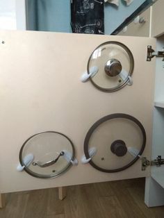 three circular glass plates mounted on a wall in a room with wood flooring and white cabinets