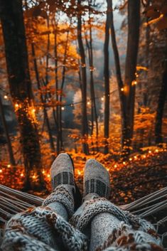 someone is laying in a hammock with their feet on the ground and lights shining through the trees behind them