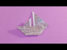 an origami boat made out of money sitting on top of a purple surface