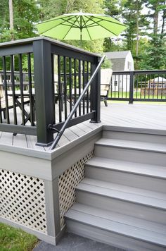 a deck with an umbrella on it and some steps leading up to the top floor