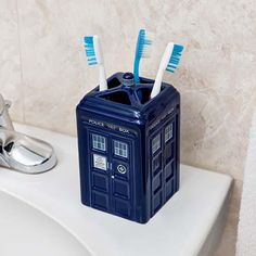 a toothbrush holder with two toothbrushes in it sitting on a bathroom sink