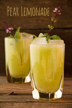 two glasses filled with lemonade sitting on top of a wooden table