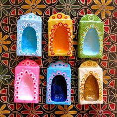 four different colored clay pots sitting next to each other on a colorful wallpapered surface