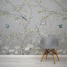 a chair sitting in front of a wallpapered with birds and flowers on it