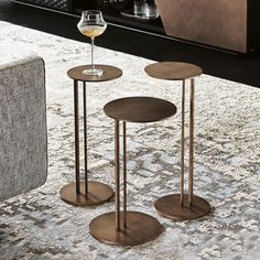 three tables with wine glasses on them in front of a couch and coffee table next to it