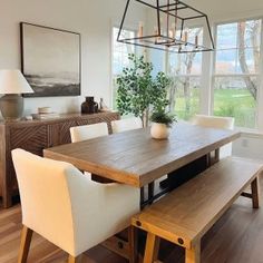 a dining room table with white chairs and a wooden bench