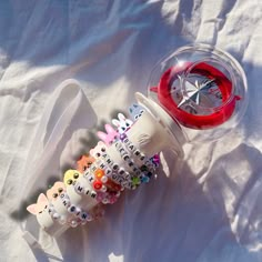 a glass cup filled with lots of different types of beads next to a plastic container