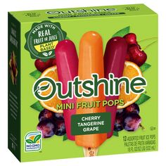 an orange and pink popsicle with fruit on the top, in front of a green box