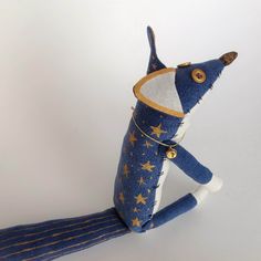 a blue and white stuffed animal with gold stars on it's tail, sitting in front of a white background