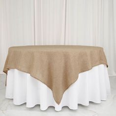 the table is covered with a tan and white linen overflowing from the top