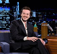 a man in a suit and tie sitting on a couch