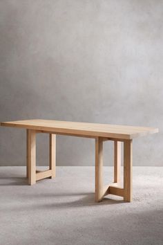 a wooden table sitting on top of a white carpeted floor next to a gray wall