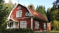 a red house with white windows and trees in the background