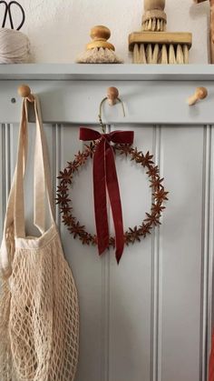 a bag hanging on the wall next to a wreath with red ribbon tied around it