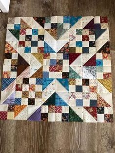 a patchwork quilt is laying on the floor in front of a wooden table top