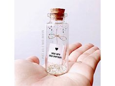 a hand holding a tiny bottle with a message inside