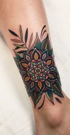 a woman's foot with a flower tattoo on the side of her leg,