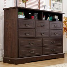 a brown dresser with many drawers in the middle and a plant on top of it