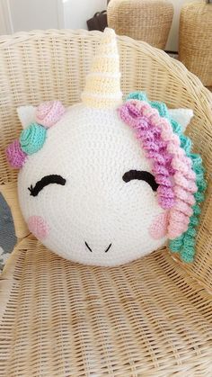 a crocheted unicorn pillow sitting on top of a wicker chair